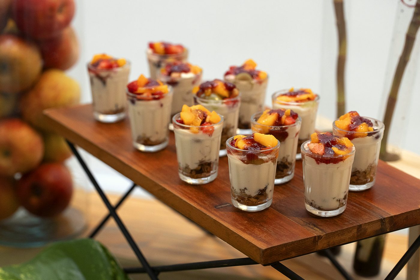 Copinhos de iogurte com granola e frutas sobre mesa de madeira
