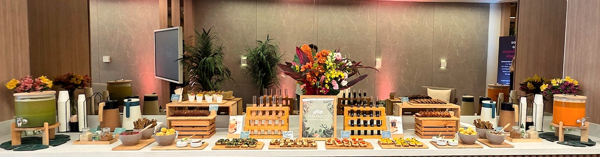 Buffet do catering Purana montado dentro de uma empresa, com suco verde, shots e finger foods