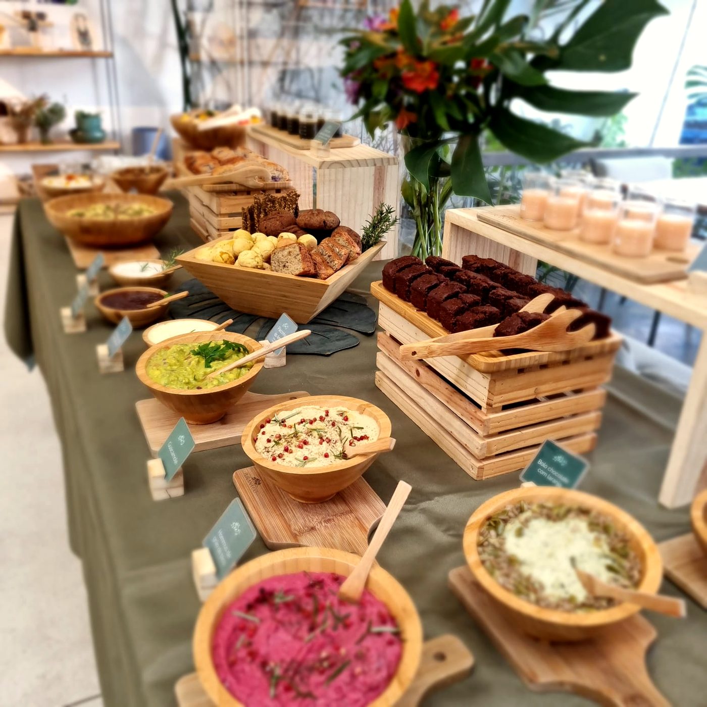 Mesa de catering com guacamole, hummus, pasta de beterraba e cesto de pães